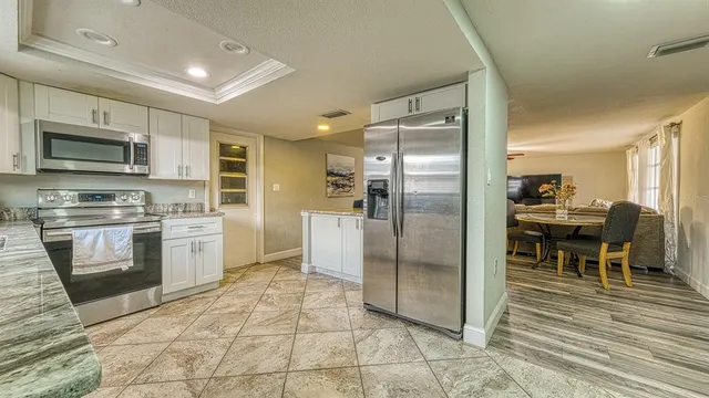 a kitchen with stainless steel appliances granite countertop a refrigerator a stove a microwave oven a sink with island and chairs