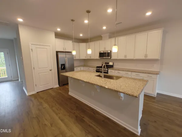 a large kitchen with stainless steel appliances a large counter top a sink a refrigerator and a stove