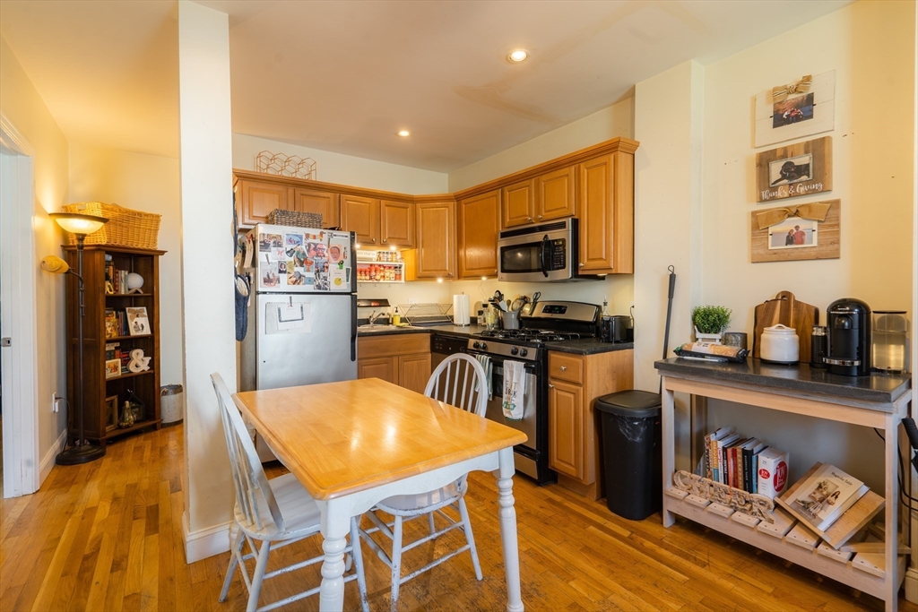 328 Beacon Street, Unit 1F Somerville, MA 02143 - Photo 2 of 10 a kitchen with stainless steel appliances granite countertop a refrigerator a stove top oven a sink dishwasher and white cabinets with wooden floor