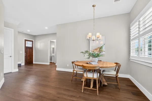 a dining room with furniture a chandelier and wooden floor