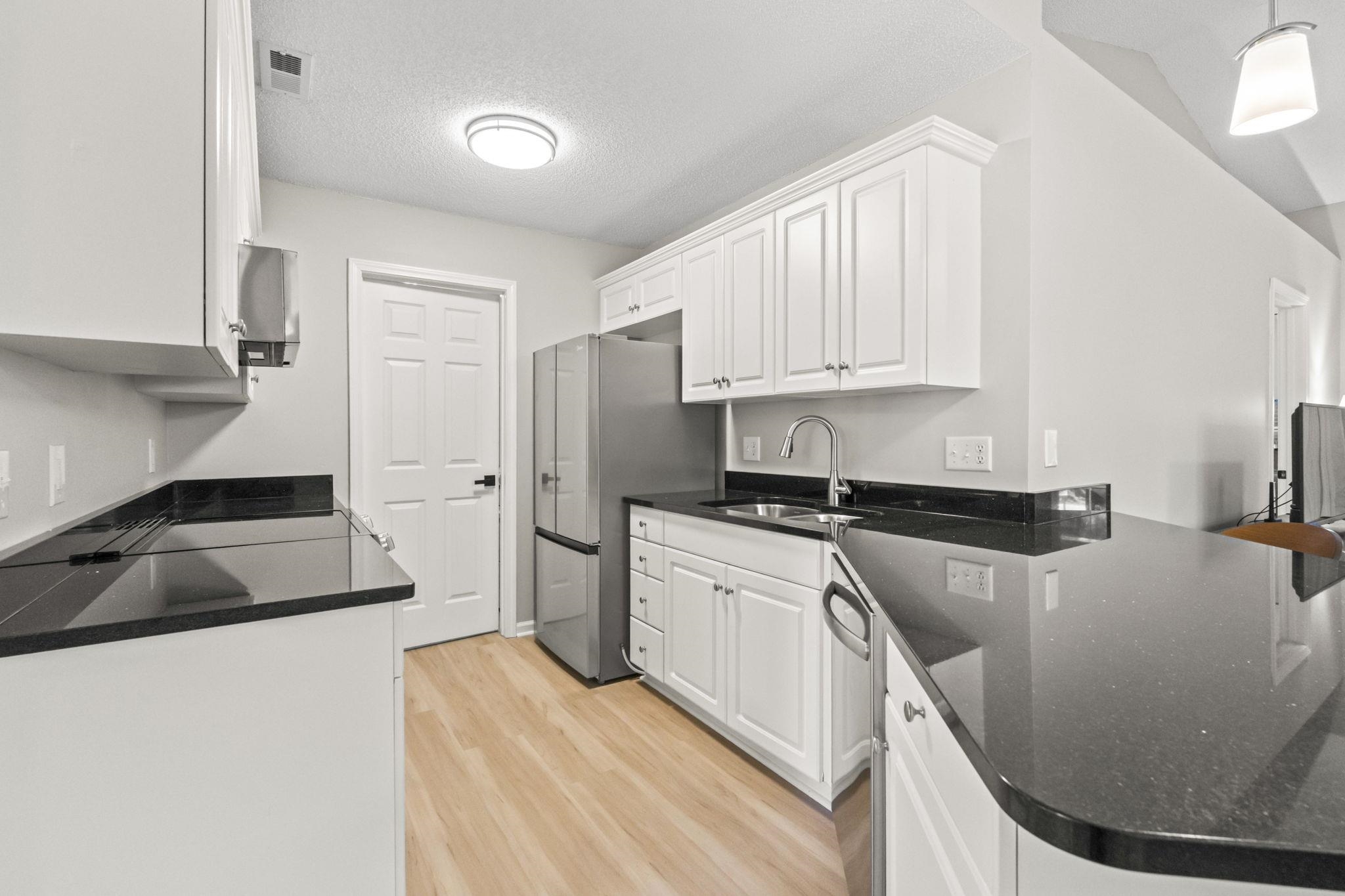 135 Country Manor Drive, Unit B Conway, SC 29526 - Photo 4 of 40 Kitchen featuring white cabinetry, stainless steel appliances, light wood-type flooring, dark stone counters, and a textured ceiling