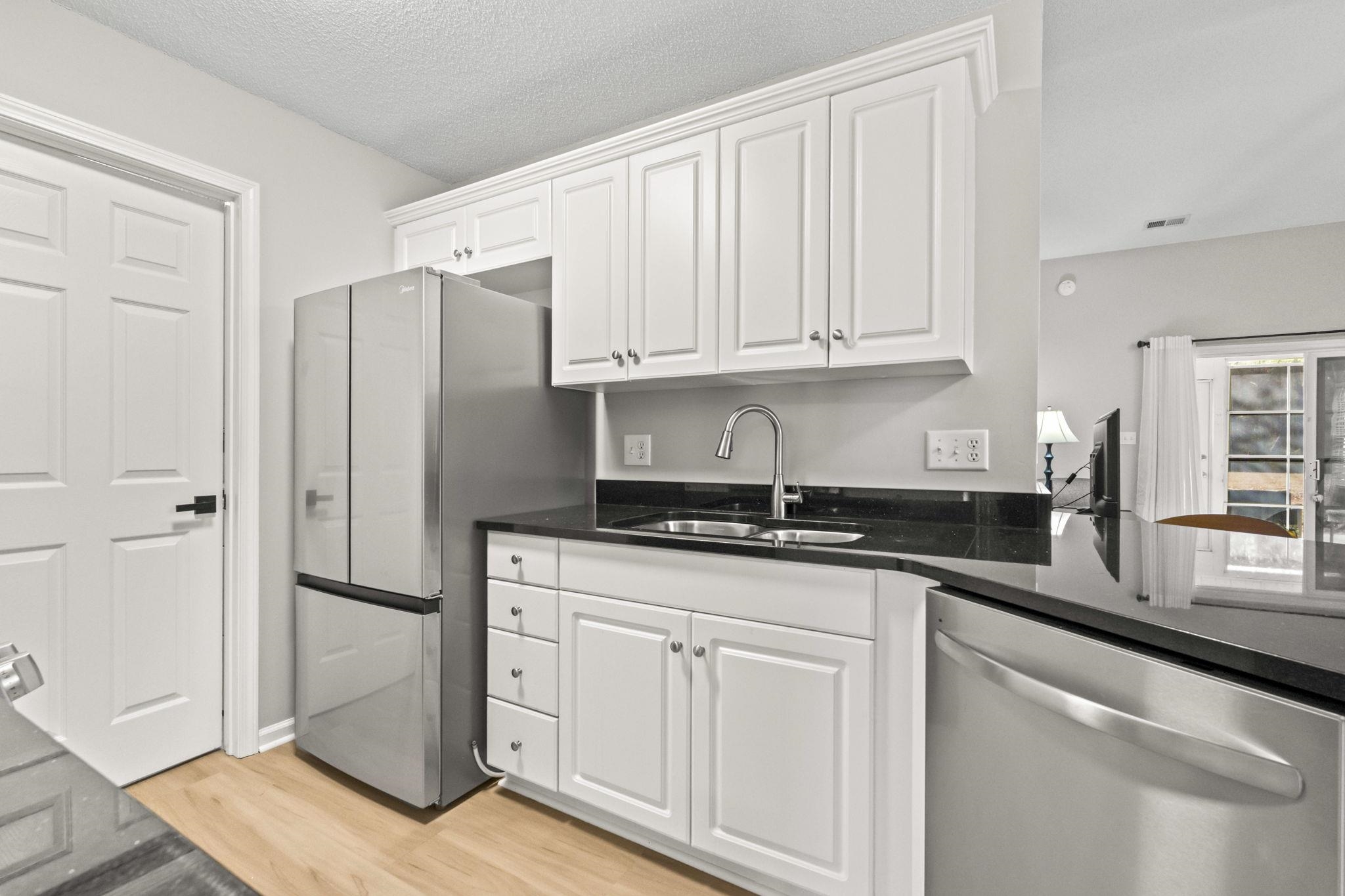 135 Country Manor Drive, Unit B Conway, SC 29526 - Photo 5 of 40 Kitchen featuring appliances with stainless steel finishes, white cabinetry, dark stone countertops, light wood-style flooring, and a textured ceiling