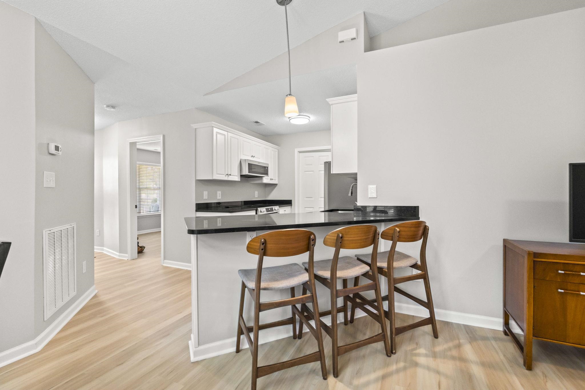 135 Country Manor Drive, Unit B Conway, SC 29526 - Photo 8 of 40 Kitchen with a peninsula, a kitchen bar, white cabinetry, hanging light fixtures, and light wood finished floors