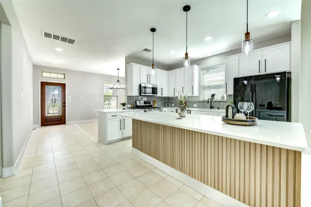 a kitchen with stainless steel appliances kitchen island granite countertop a sink a counter top space cabinets and a window