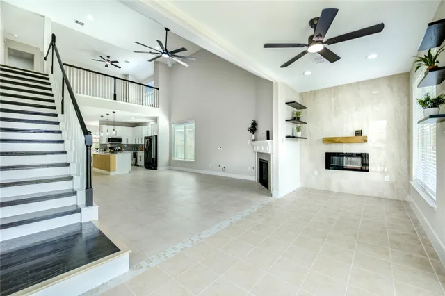 a view of a livingroom with a fireplace a ceiling fan and stairs