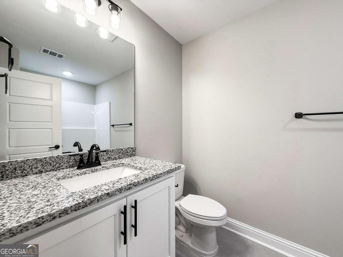 411 Madison Avenue St. Marys, GA 31558 - Photo 15 of 41 a bathroom with a granite countertop sink a toilet and a mirror