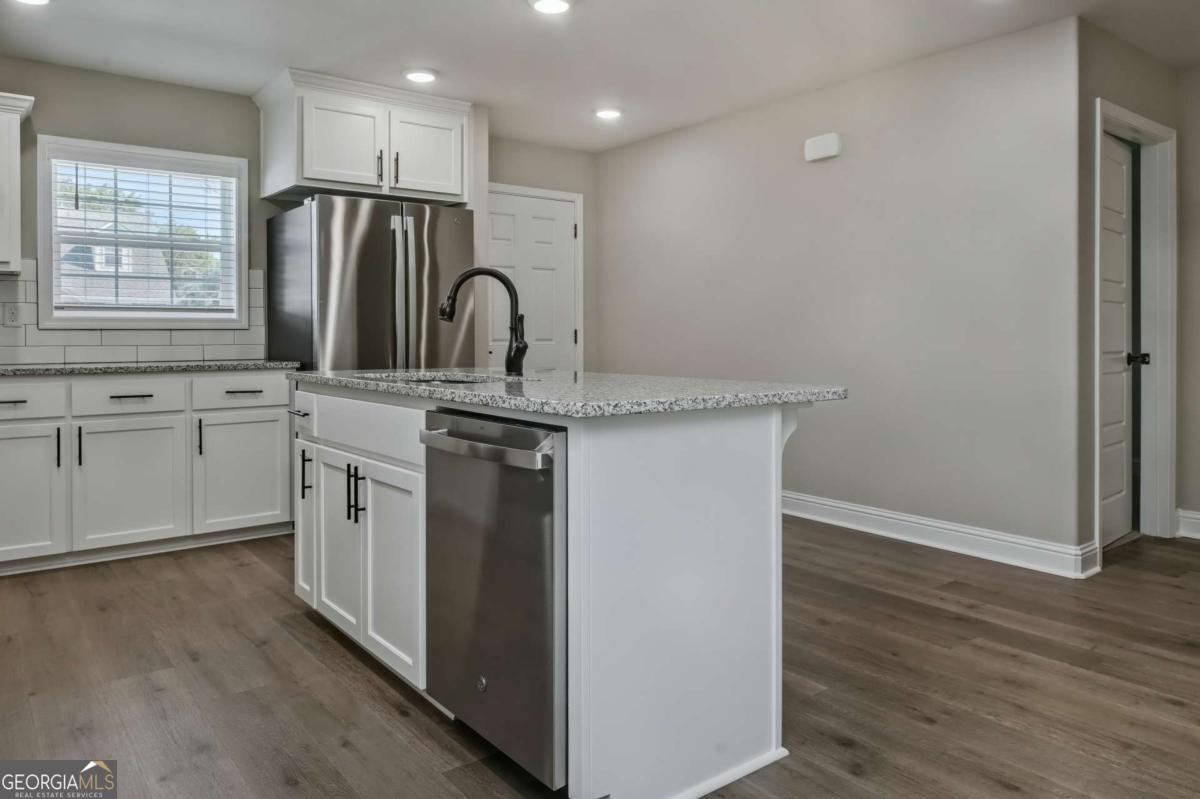 411 Madison Avenue St. Marys, GA 31558 - Photo 6 of 41 a kitchen with stainless steel appliances granite countertop a sink a stove a refrigerator and island with wooden floor