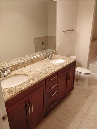 a spacious bathroom with a granite countertop sink a toilet and bathtub