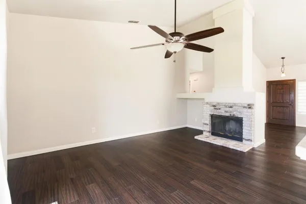 an empty room with wooden floor a fireplace and windows