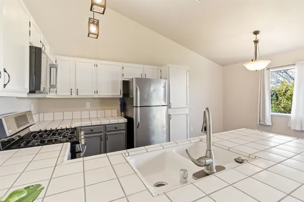 a kitchen with granite countertop a refrigerator and a stove top oven