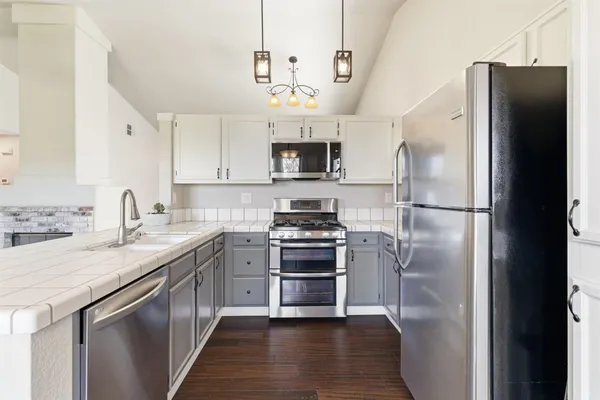 a kitchen with stainless steel appliances granite countertop a refrigerator a stove a sink and a microwave