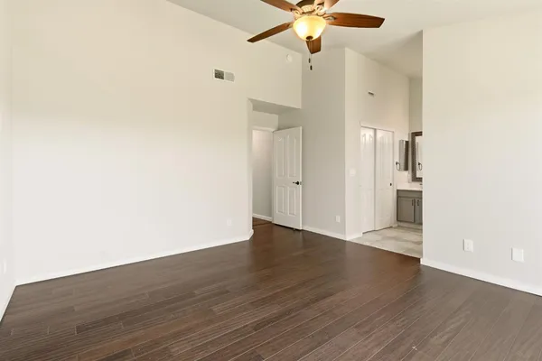 an empty room with wooden floor and ceiling fan