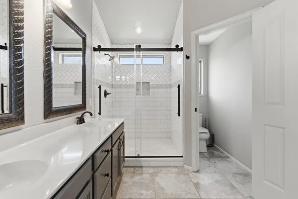 a bathroom with a granite countertop sink a toilet and shower