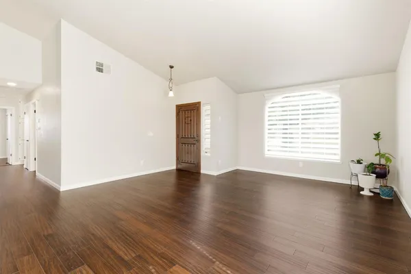 a view of an empty room with wooden floor and a window
