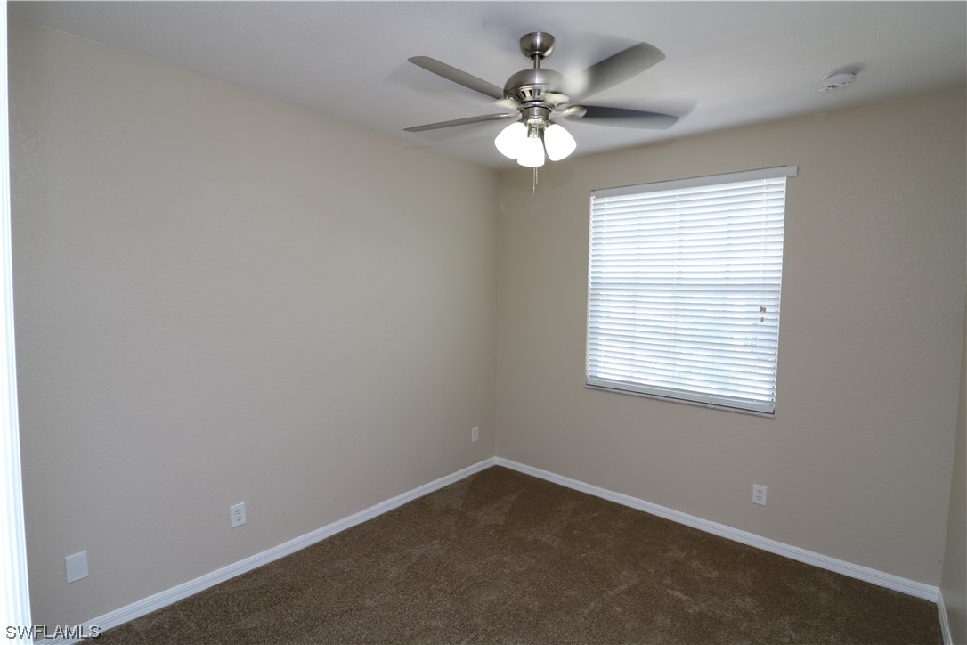 8889 Spring Mountain Way Fort Myers, FL 33908 - Photo 14 of 17 an empty room with a chandelier fan and windows