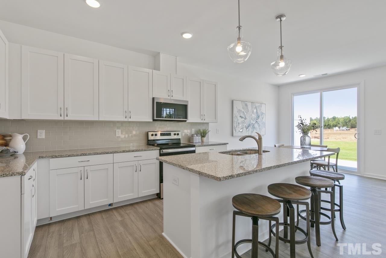 196 Lennei Lane Garner, NC 27529 - Photo 8 of 46 a large white kitchen with granite countertop lots of counter space white cabinets and stainless steel appliances