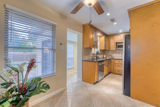 a kitchen with stainless steel appliances granite countertop a refrigerator a sink a stove and a window