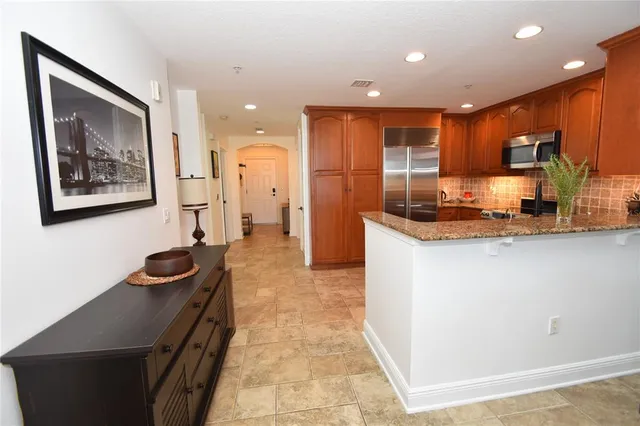 a kitchen with stainless steel appliances granite countertop a refrigerator a sink a stove and a wooden cabinets