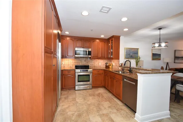 a kitchen with granite countertop kitchen island stainless steel appliances a refrigerator a stove a sink a dining table and chairs