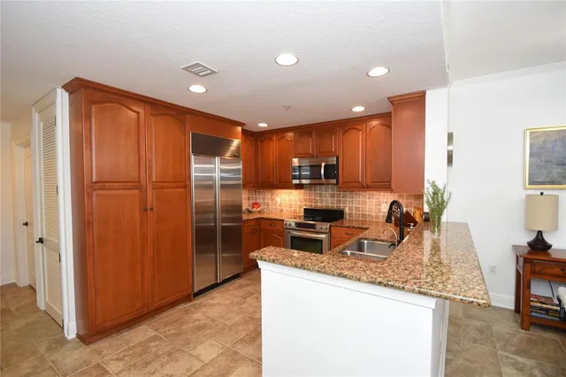 a kitchen with stainless steel appliances granite countertop a sink a stove cabinets and a refrigerator