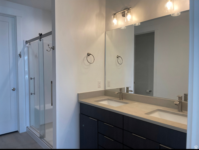 655 Oliver Road Tooele, UT 84074 - Photo 10 of 21 Modern primary bathroom featuring a dual-sink vanity with a light-finish countertop, black cabinetry with multiple drawers, and polished chrome fixtures