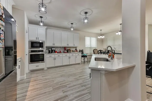 a kitchen with stainless steel appliances granite countertop a sink dishwasher and a refrigerator with wooden floor