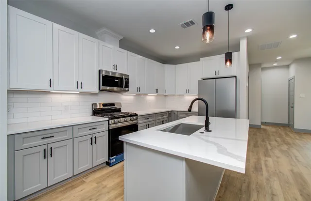 a kitchen with kitchen island a sink stainless steel appliances and cabinets