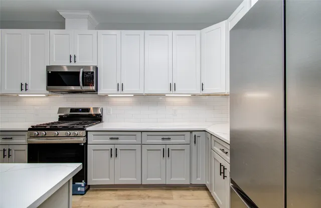 a kitchen with stainless steel appliances granite countertop a stove a sink and a microwave