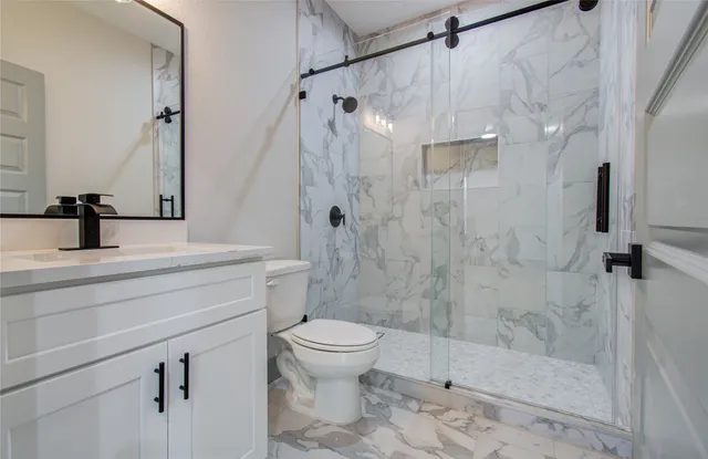 a bathroom with a shower sink vanity mirror and toilet