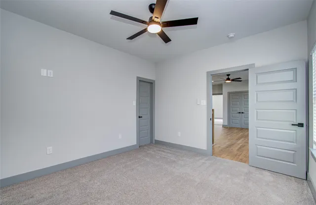 an empty room with closet and a ceiling fan