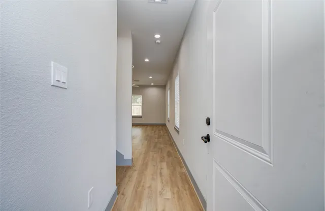 a view of a hallway with wooden floor and a bathroom