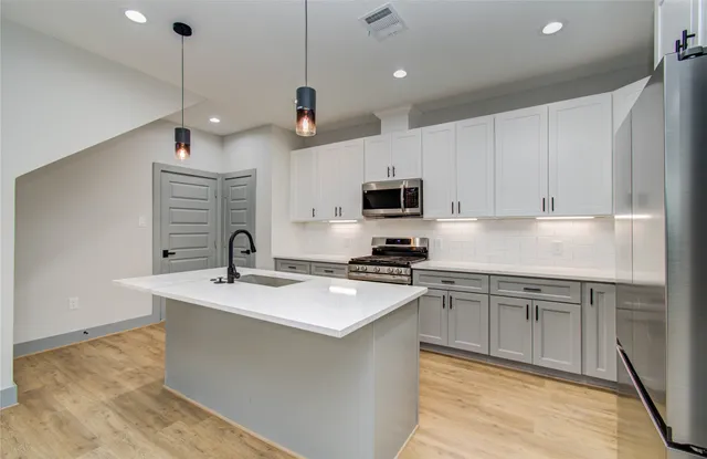 a kitchen with stainless steel appliances granite countertop a sink a stove and a refrigerator