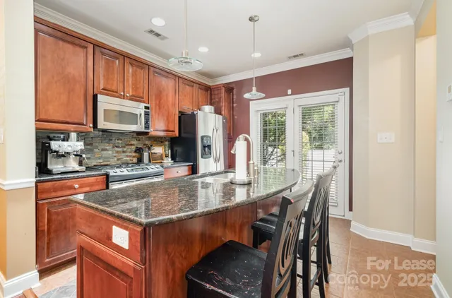 a kitchen with stainless steel appliances granite countertop a stove a refrigerator a sink a dining table and chairs with wooden floor