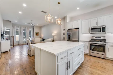 a large kitchen with kitchen island a stove a sink a center island and wooden floor