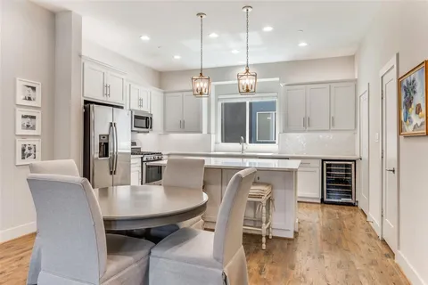 a kitchen with stainless steel appliances granite countertop a stove a refrigerator a kitchen island a dining table and chairs with wooden floor