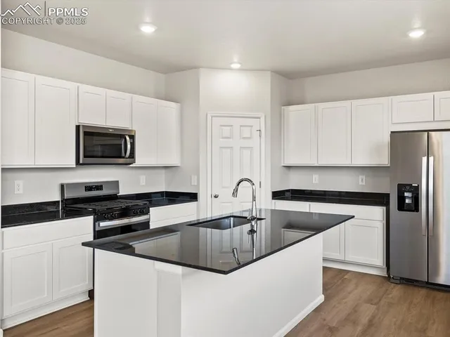 a kitchen with stainless steel appliances granite countertop a sink a stove a microwave and cabinets