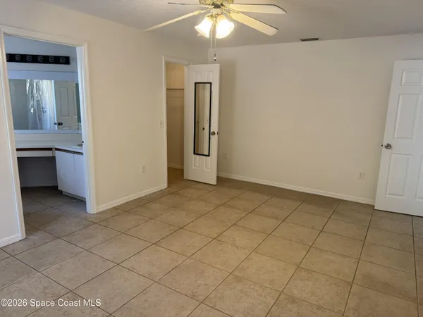 a view of an empty room with chandelier fan