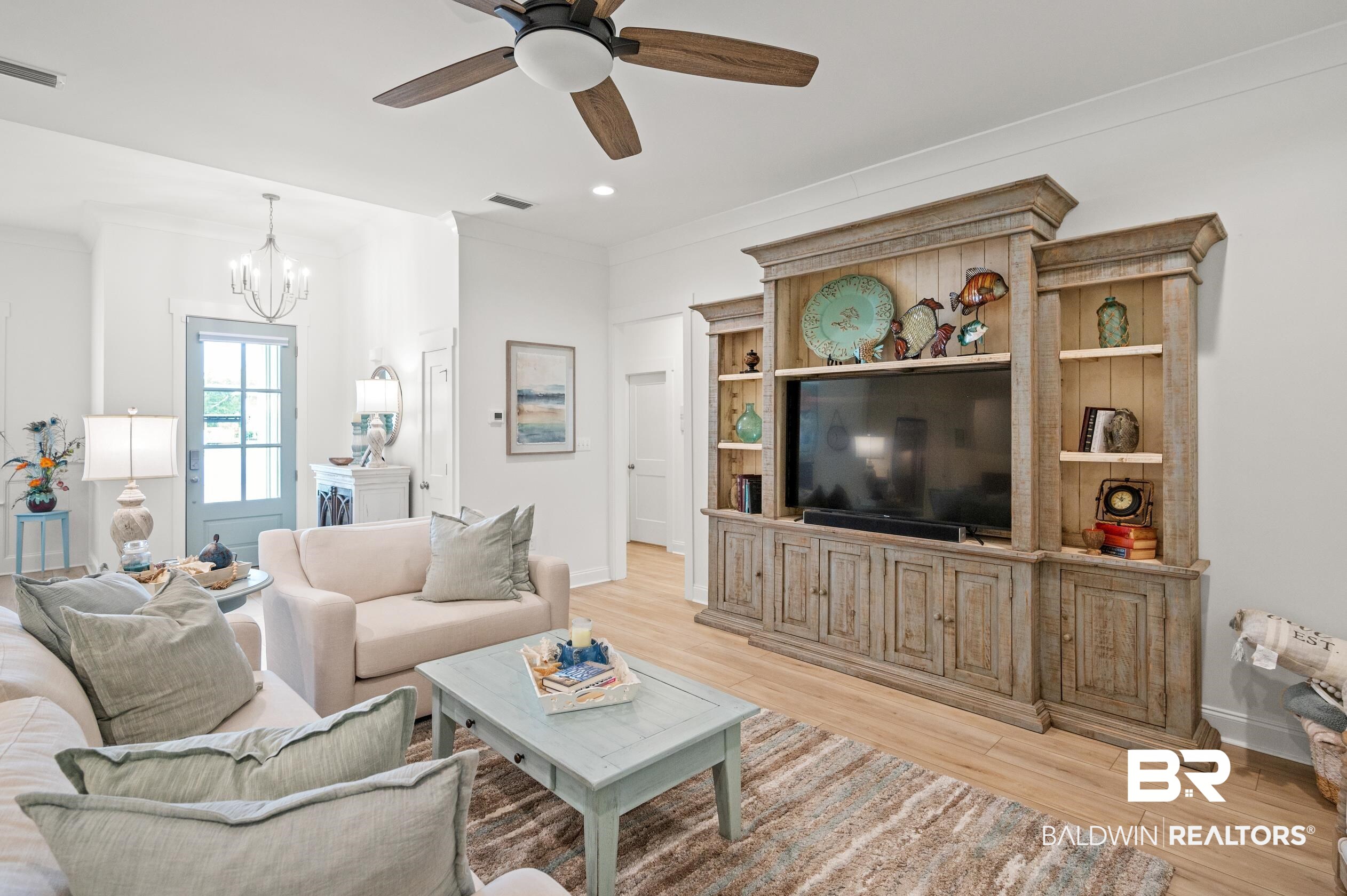 4601 Surrey Lane Orange Beach, AL 36561 - Photo 7 of 43 Living room featuring ceiling fan with notable chandelier, crown molding, and light hardwood / wood-style flooring