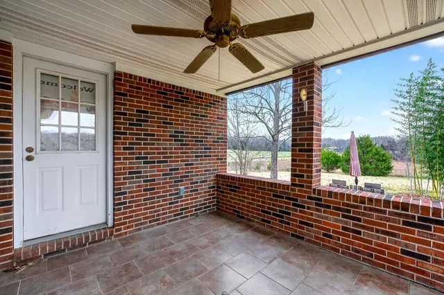 an empty room with wooden floor chandelier fan and windows