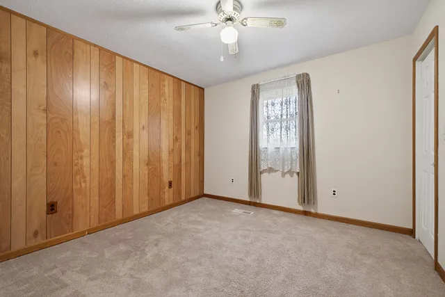 an empty room with a chandelier fan and windows