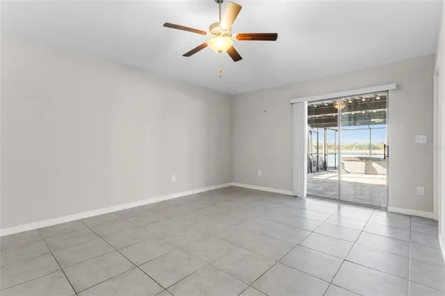 an empty room with chandelier fan and windows