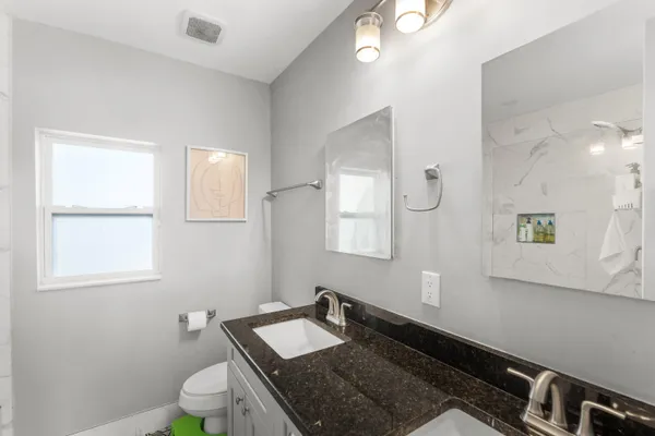 a bathroom with a granite countertop sink a toilet and mirror