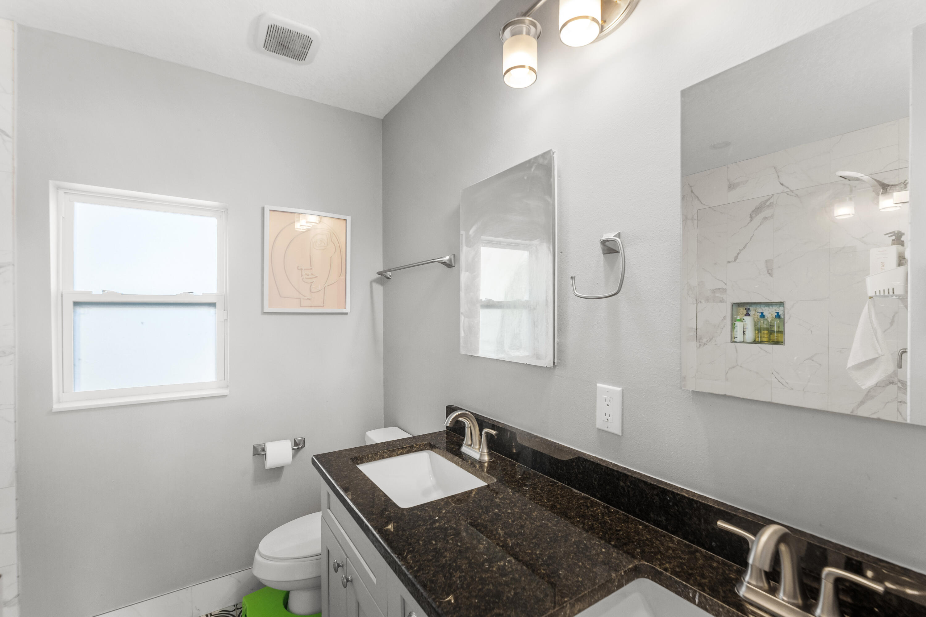 3037 Southeast Iris Street Stuart, FL 34997 - Photo 20 of 36 a bathroom with a granite countertop sink a toilet and mirror