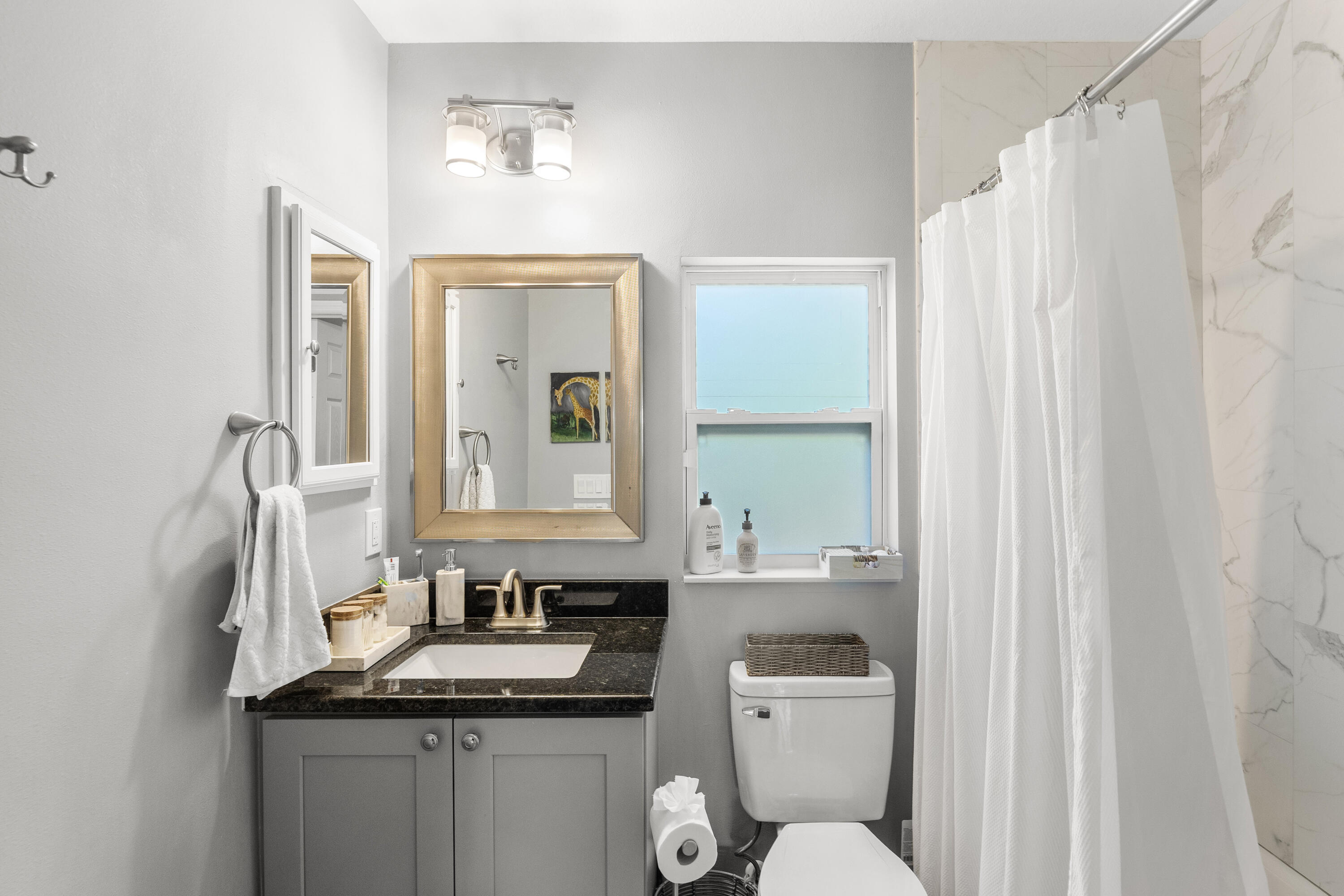 3037 Southeast Iris Street Stuart, FL 34997 - Photo 26 of 36 a bathroom with a granite countertop sink toilet and mirror