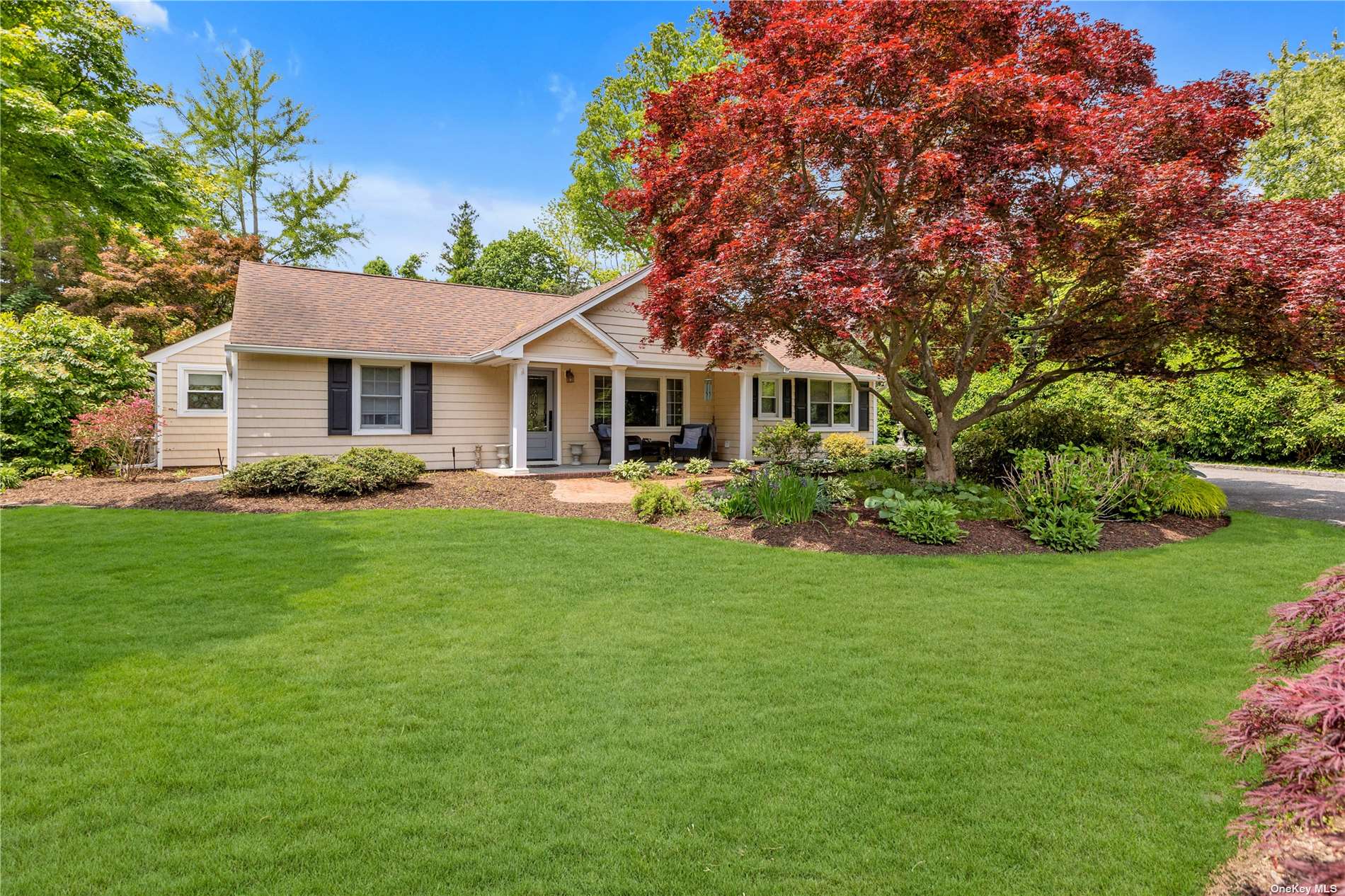 a front view of a house with a garden and trees