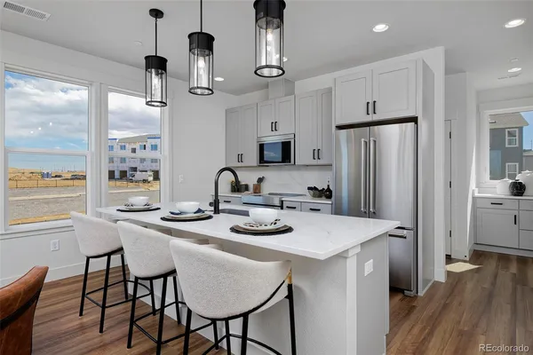 a kitchen with stainless steel appliances kitchen island granite countertop a dining table chairs stove and refrigerator