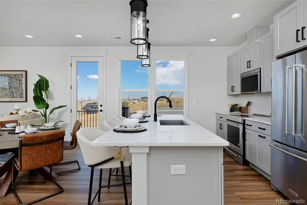a kitchen with stainless steel appliances granite countertop a sink a stove and a wooden floor