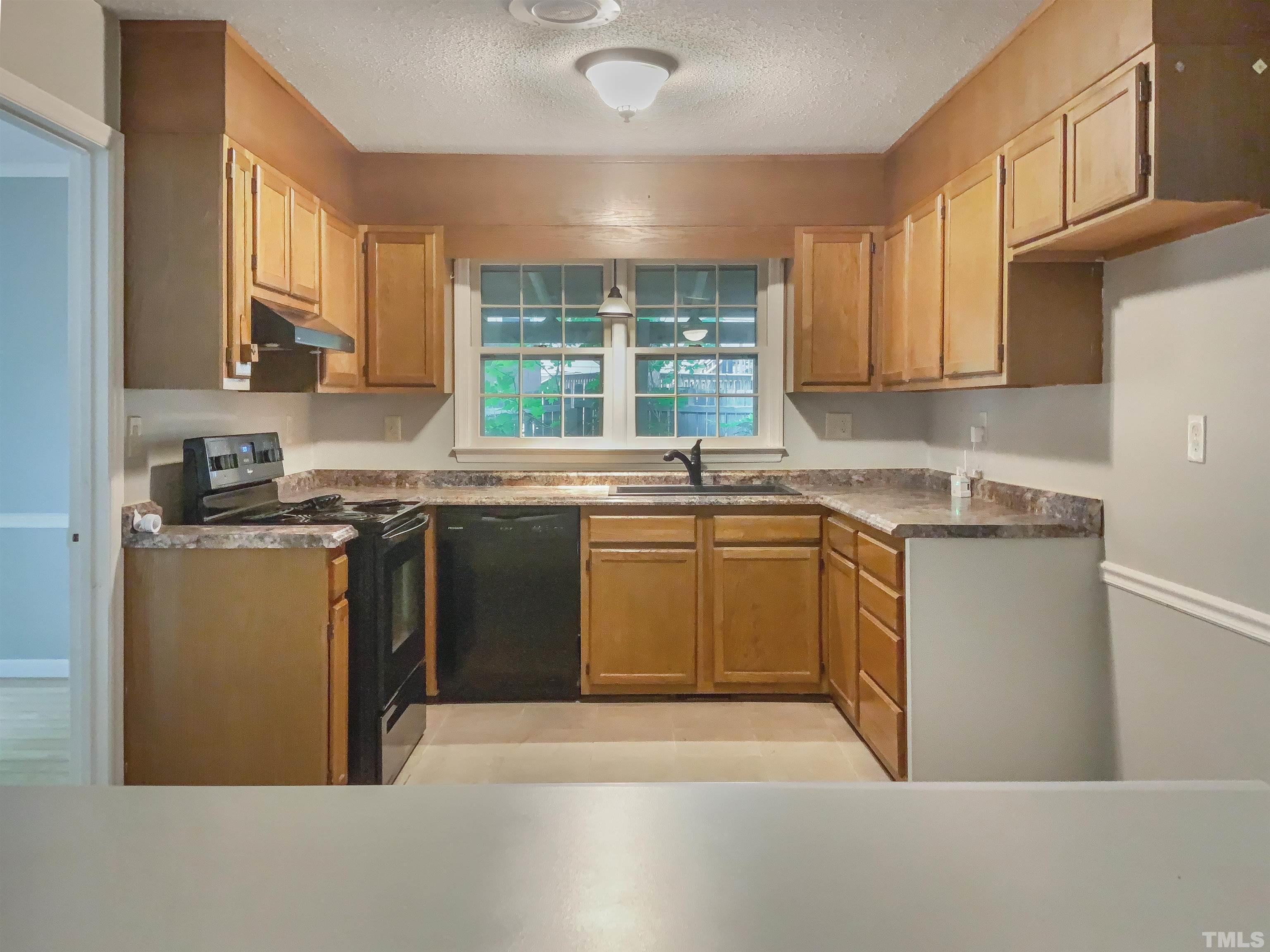 7312 Mine Valley Road Raleigh, NC 27615 - Photo 4 of 19 a kitchen with a stove a sink a window and cabinets