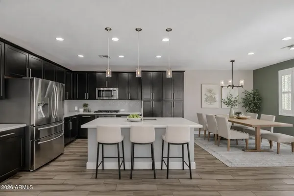 a kitchen with stainless steel appliances kitchen island granite countertop a table chairs stove and refrigerator