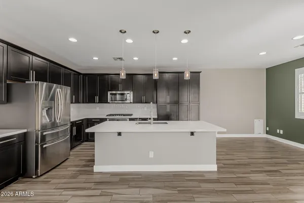 a view of a kitchen with kitchen island a sink wooden floor and stainless steel appliances